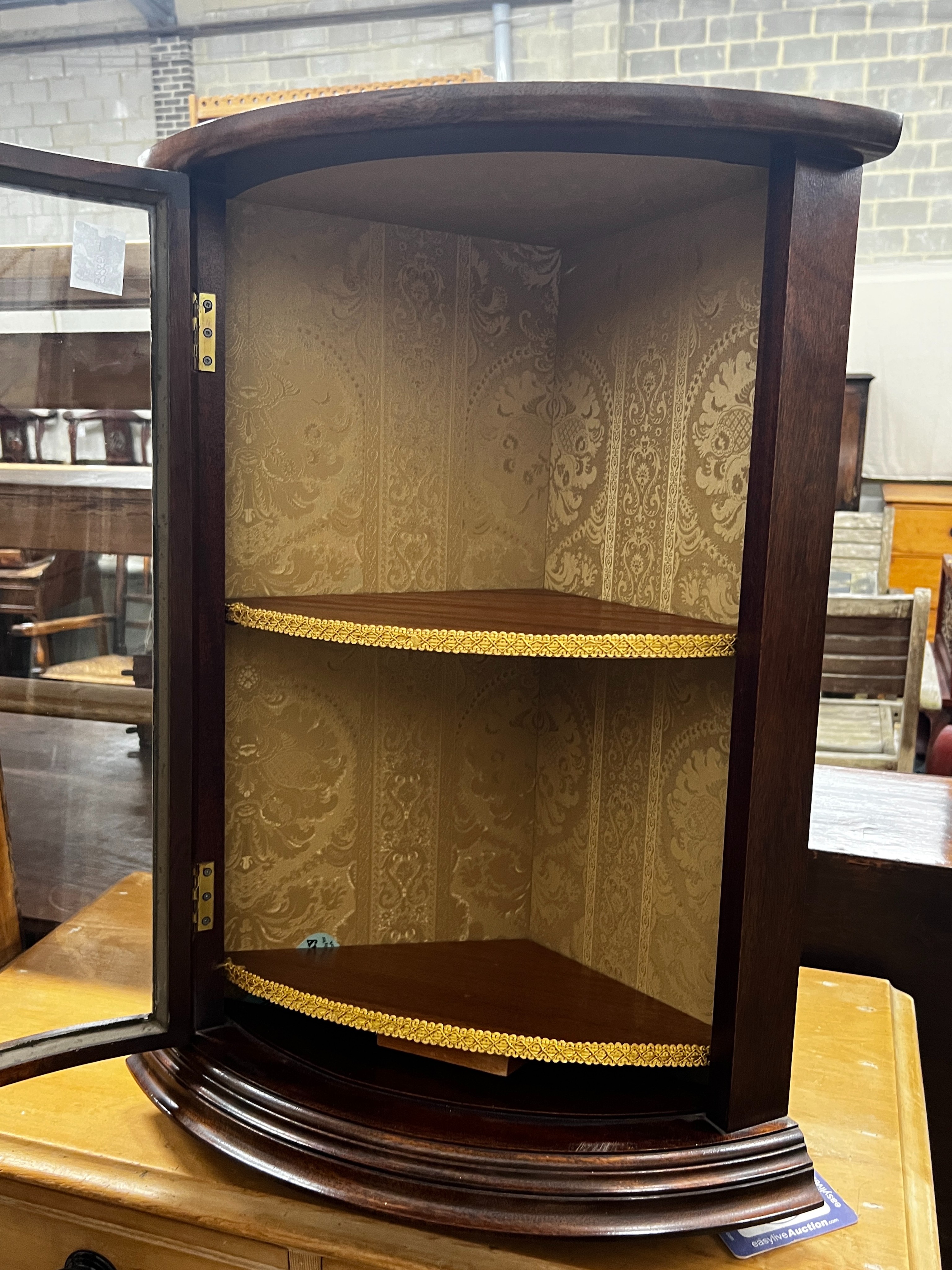 A reproduction George III style glazed mahogay bowfront hanging corner cupboard, width 49cm, depth 34cm, height 66cm